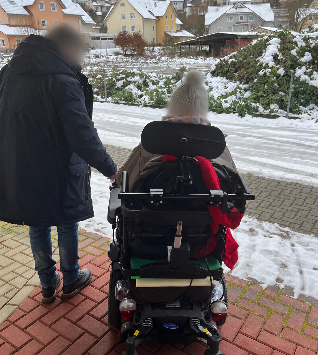 Begleiteter Spaziergang mit einem Rollstuhl im Winter.