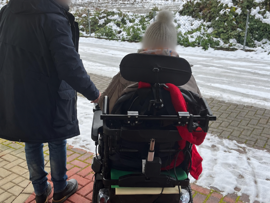 Begleiteter Spaziergang mit einem Rollstuhl im Winter.